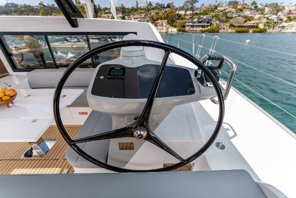 Slide: The Image of Steering wheel of 2024 Seawind 1600 yacht, overlooking serene waters and coastal homes. - 18