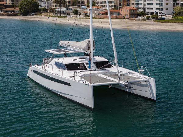 Slide: The Image of 2024 Seawind 1600 catamaran sailing near a sandy beach and coastal buildings. - 4