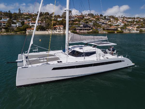 Slide: The Image of 2024 Seawind 1600 catamaran sailing near coastal homes on a sunny day. - 8
