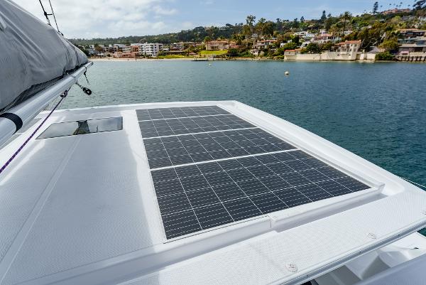 Slide: The Image of 2024 Seawind 1600 catamaran with solar panels on deck, docked near coastal homes. - 9