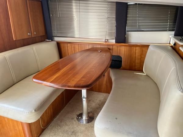 Slide: The Image of Interior dining area of 2001 Silverton 330 Sport Bridge yacht with wooden table and leather seating. - 18