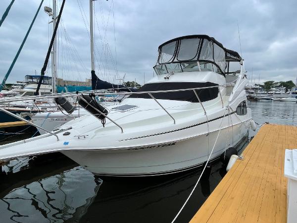 Slide: The Image of 2007 Silverton 330 Sport Bridge yacht docked at marina, featuring sleek white design. - 1