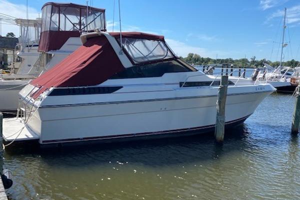 Slide: The Image of 1990 Silverton 34 Express boat docked at a marina with red canopy. - 0