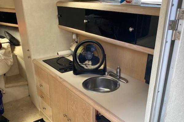 Slide: The Image of Compact kitchen area in a 1990 Silverton 34 Express boat with sink, stove, and fan. - 23