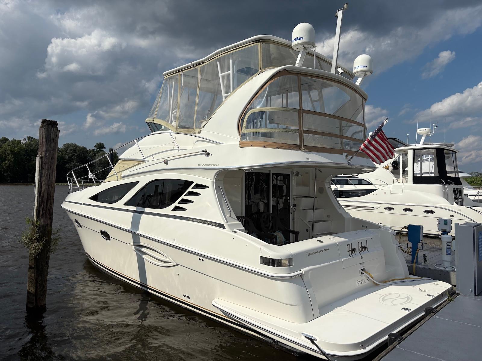 Slide: The Image of 2006 Silverton 38 Sport Bridge yacht docked, featuring sleek design and American flag. - 0