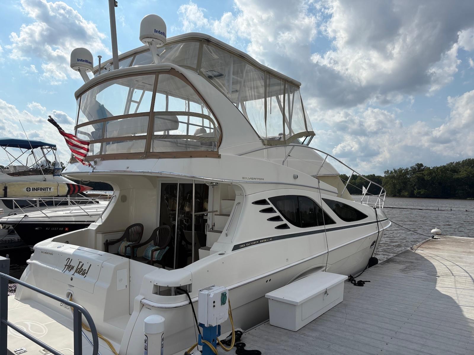 Slide: The Image of 2006 Silverton 38 Sport Bridge yacht docked under a cloudy sky. - 1