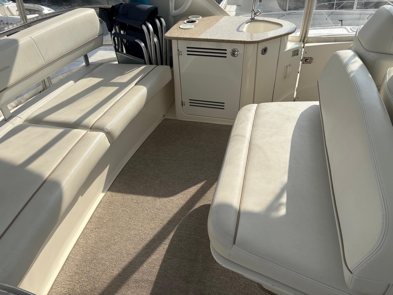 Slide: The Image of Interior of a 2006 Silverton 38 Sport Bridge with beige seating and compact kitchenette. - 10