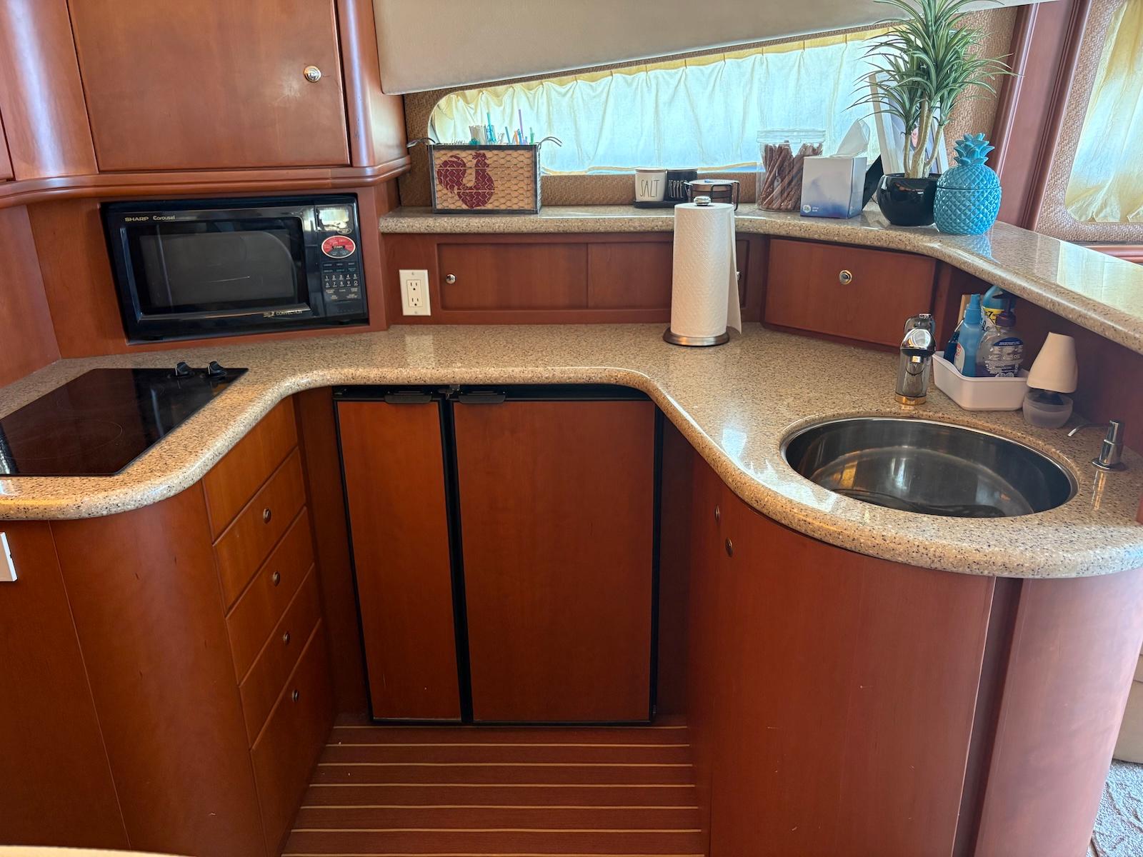Slide: The Image of 2006 Silverton 38 Sport Bridge yacht kitchen with microwave, sink, and countertop. - 24