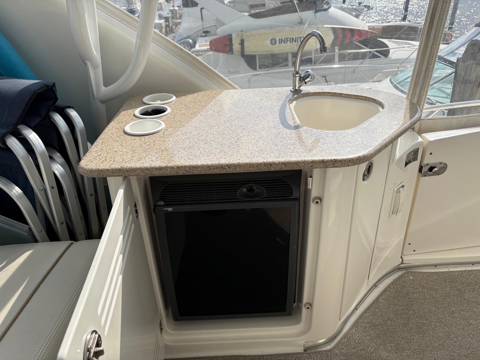 Slide: The Image of 2006 Silverton 38 Sport Bridge yacht kitchenette with sink, countertop, and mini fridge. - 8