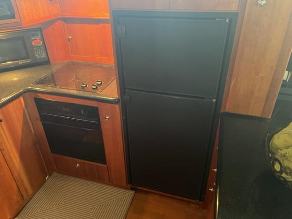 Slide: The Image of 2002 Silverton 39 Motor Yacht kitchen with stove, oven, microwave, and refrigerator. - 12