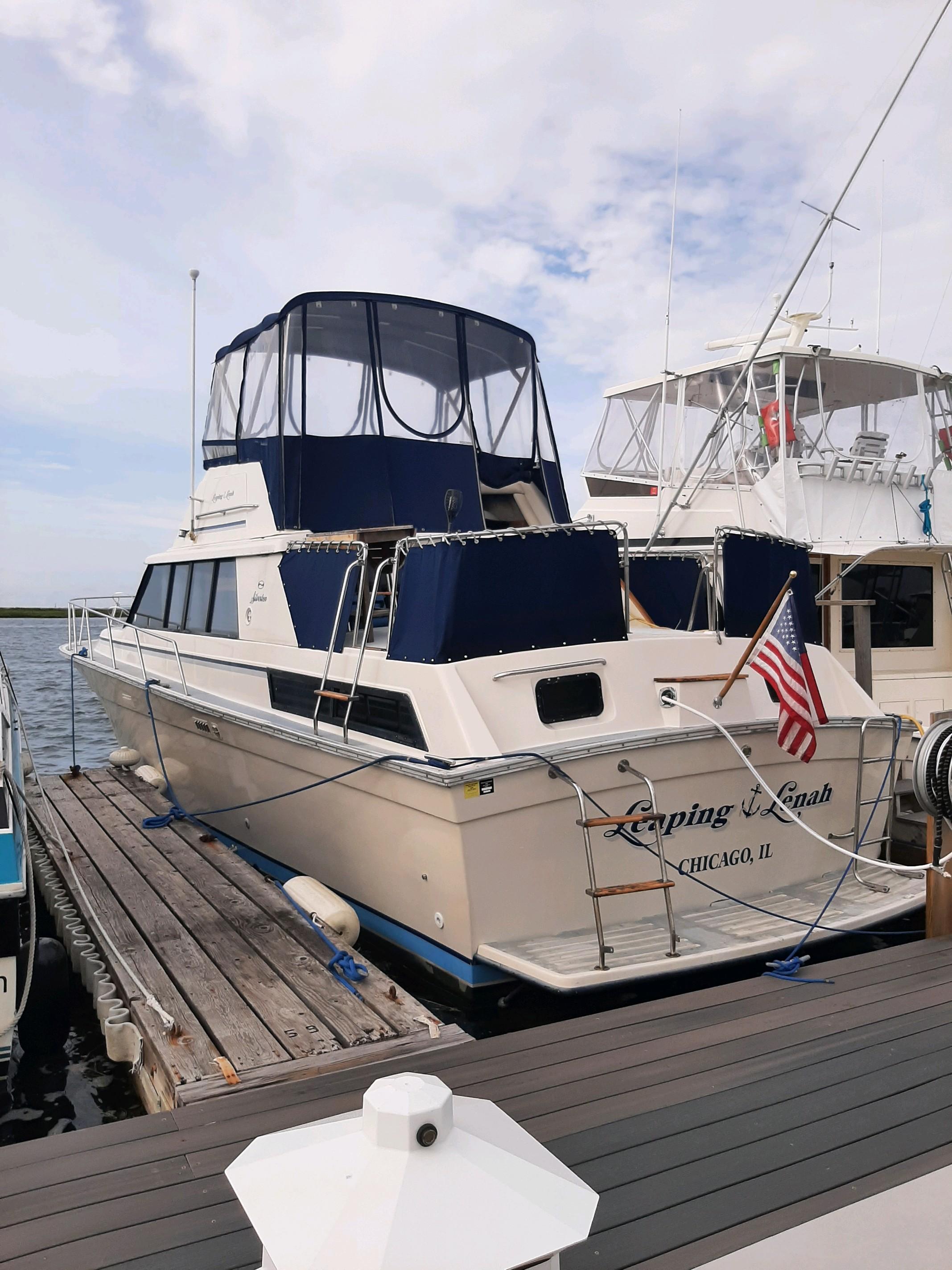 Slide: The Image of 1983 Silverton 40 Aft Cabin yacht docked, featuring blue canopy and American flag. - 0