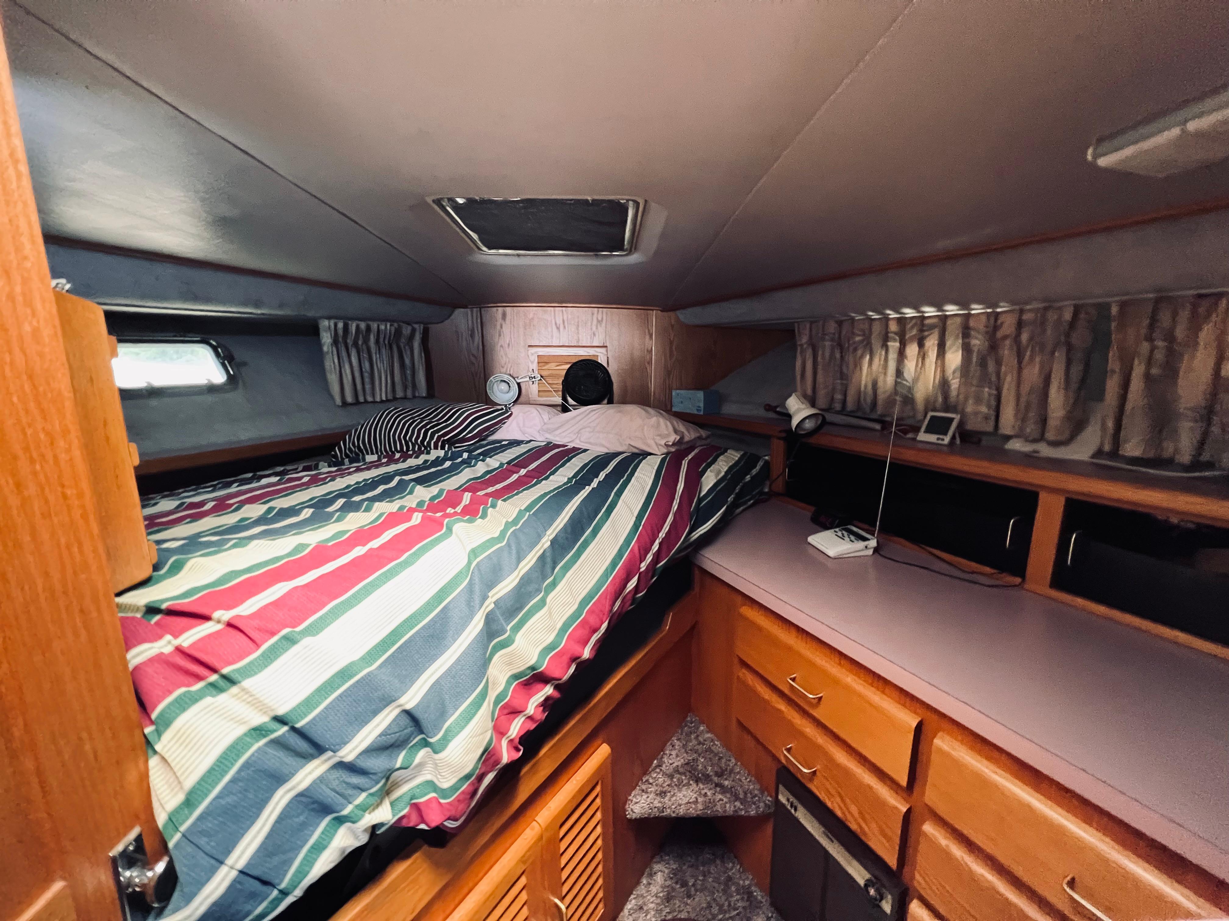 Slide: The Image of Cozy cabin interior of 1988 Silverton 40 Convertible with striped bedding and wooden cabinetry. - 11