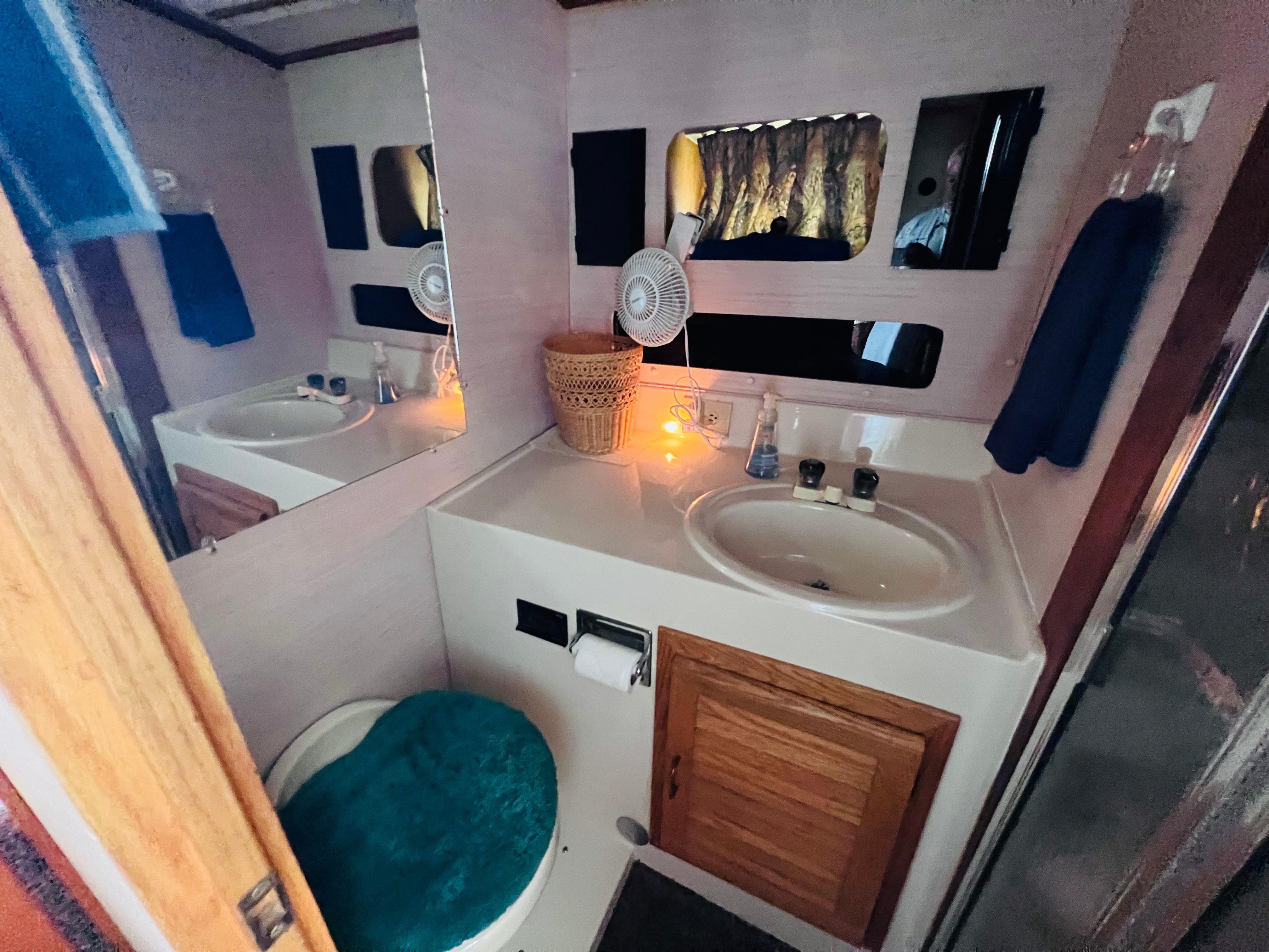 Slide: The Image of 1988 Silverton 40 Convertible bathroom with sink, mirror, and teal toilet seat cover. - 14