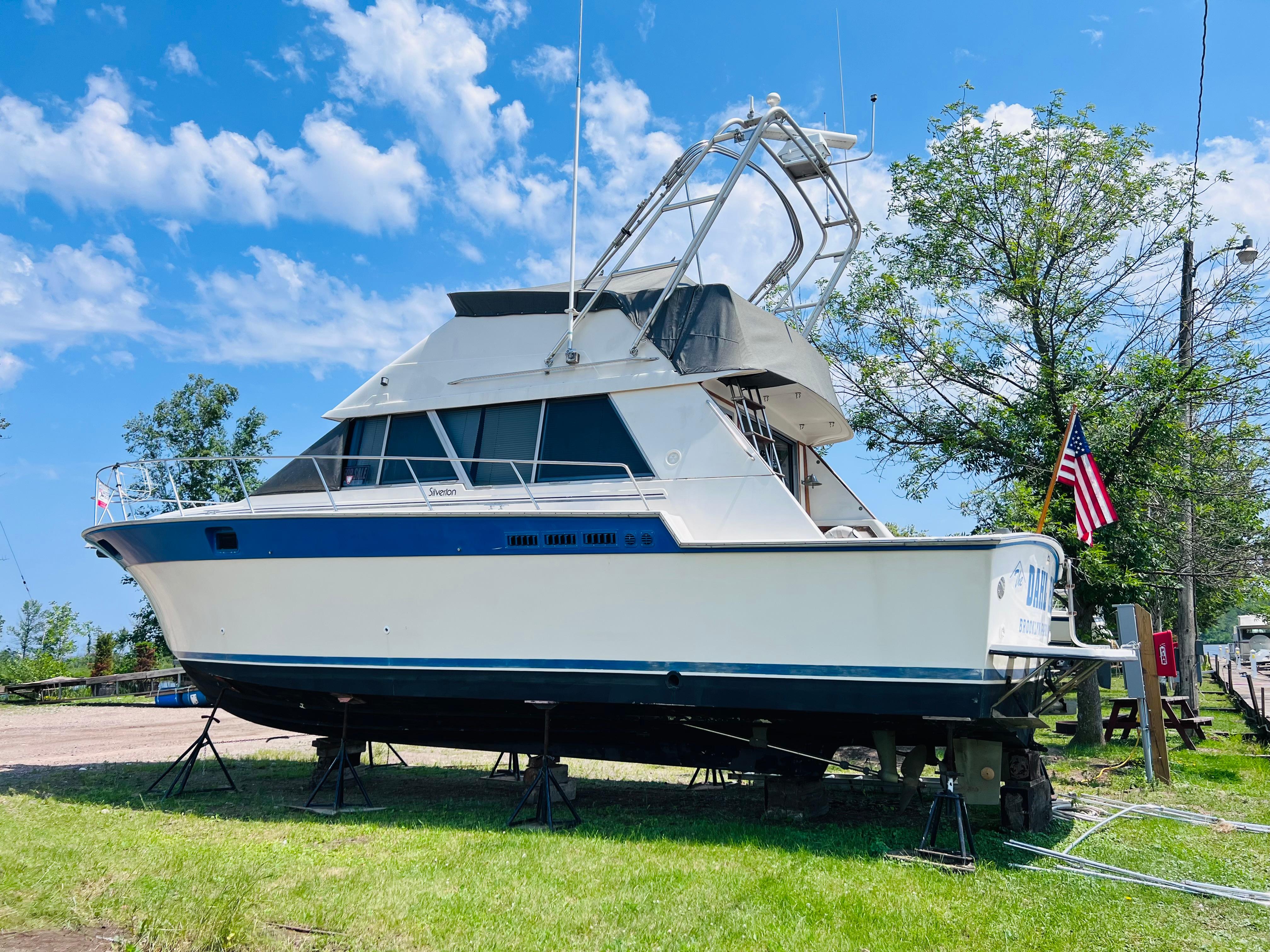 Slide: The Image of 1988 Silverton 40 Convertible boat on land, blue sky background, American flag displayed. - 3