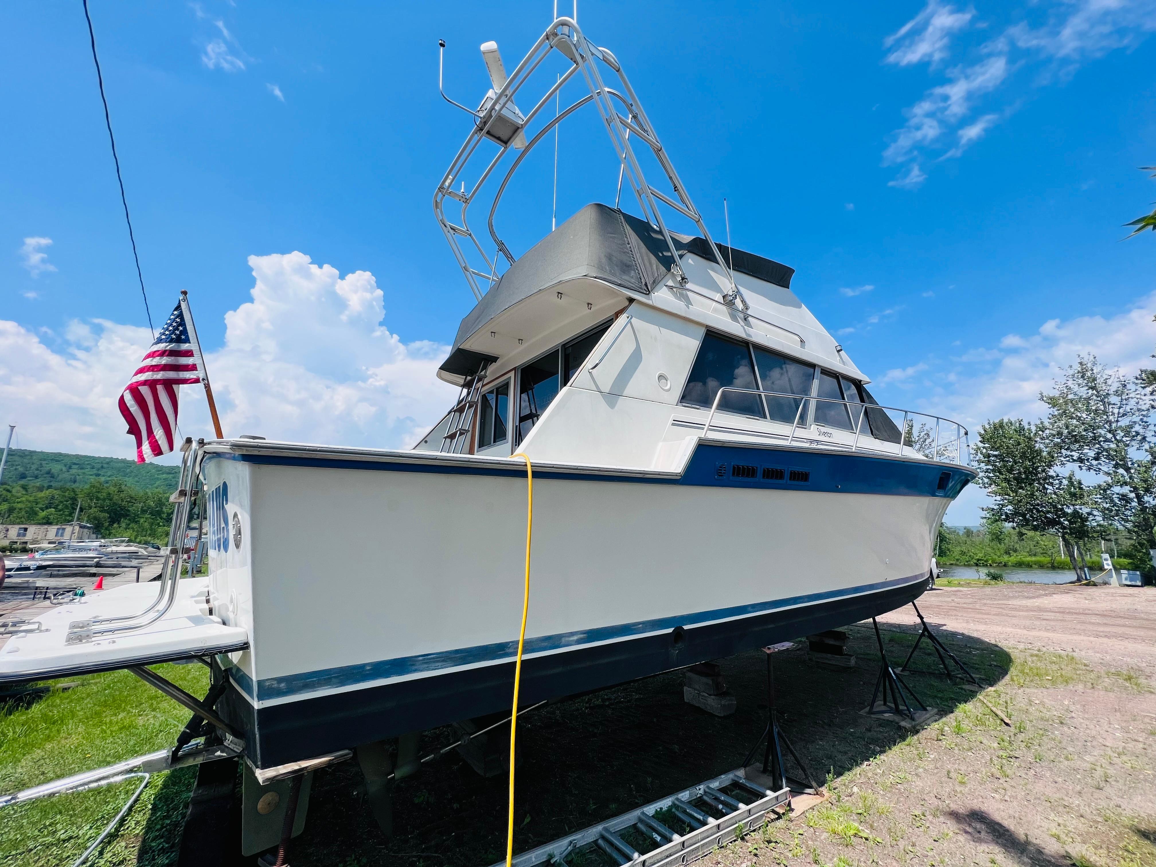 Slide: The Image of 1988 Silverton 40 Convertible boat on land, American flag, clear blue sky background. - 4
