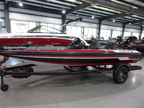 Slide: The Image of 2024 Skeeter ZX-150 bass boat in showroom, black and red design. - 1