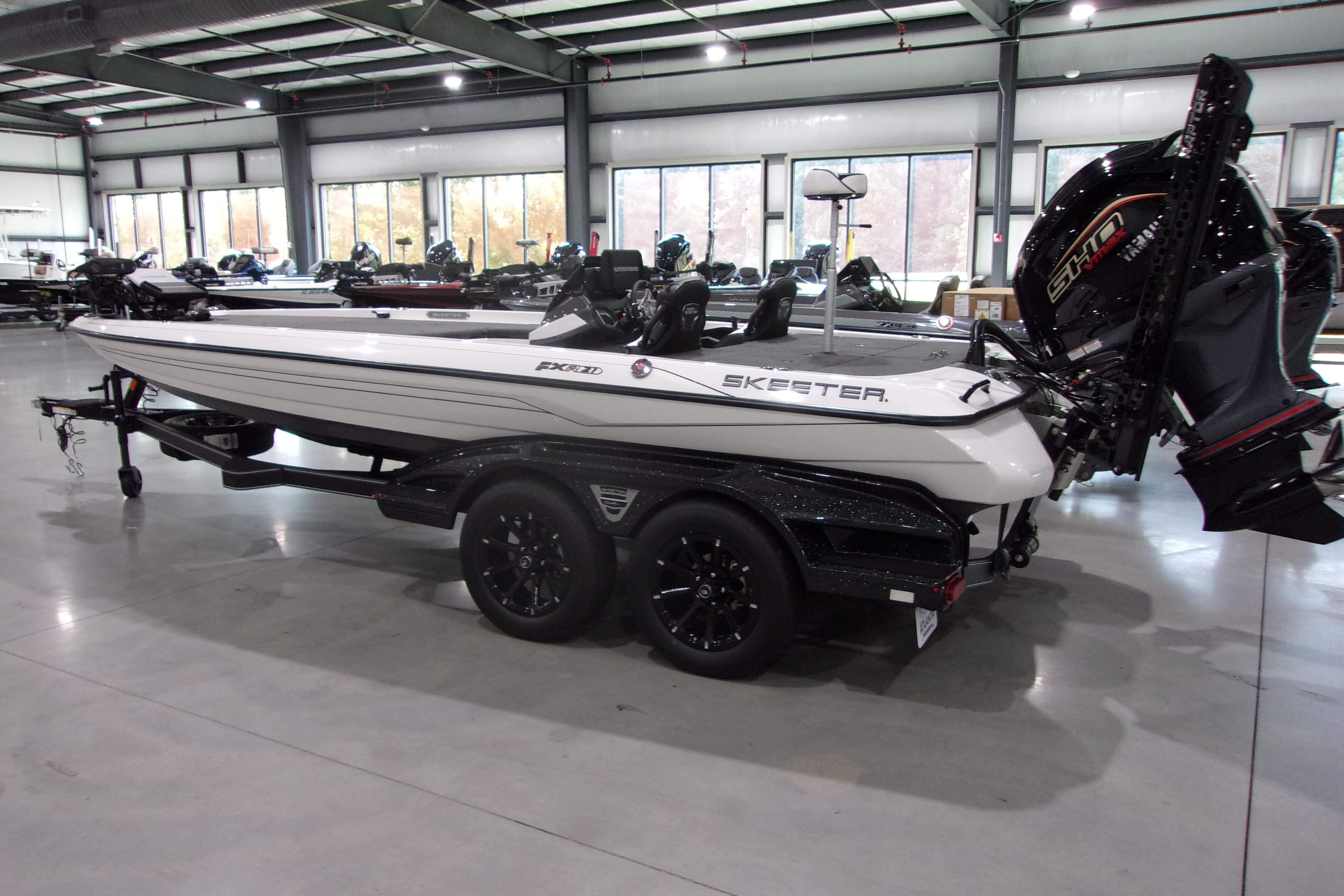Slide: The Image of 2025 Skeeter FXR21 Limited boat in showroom, side view with trailer and motor. - 1