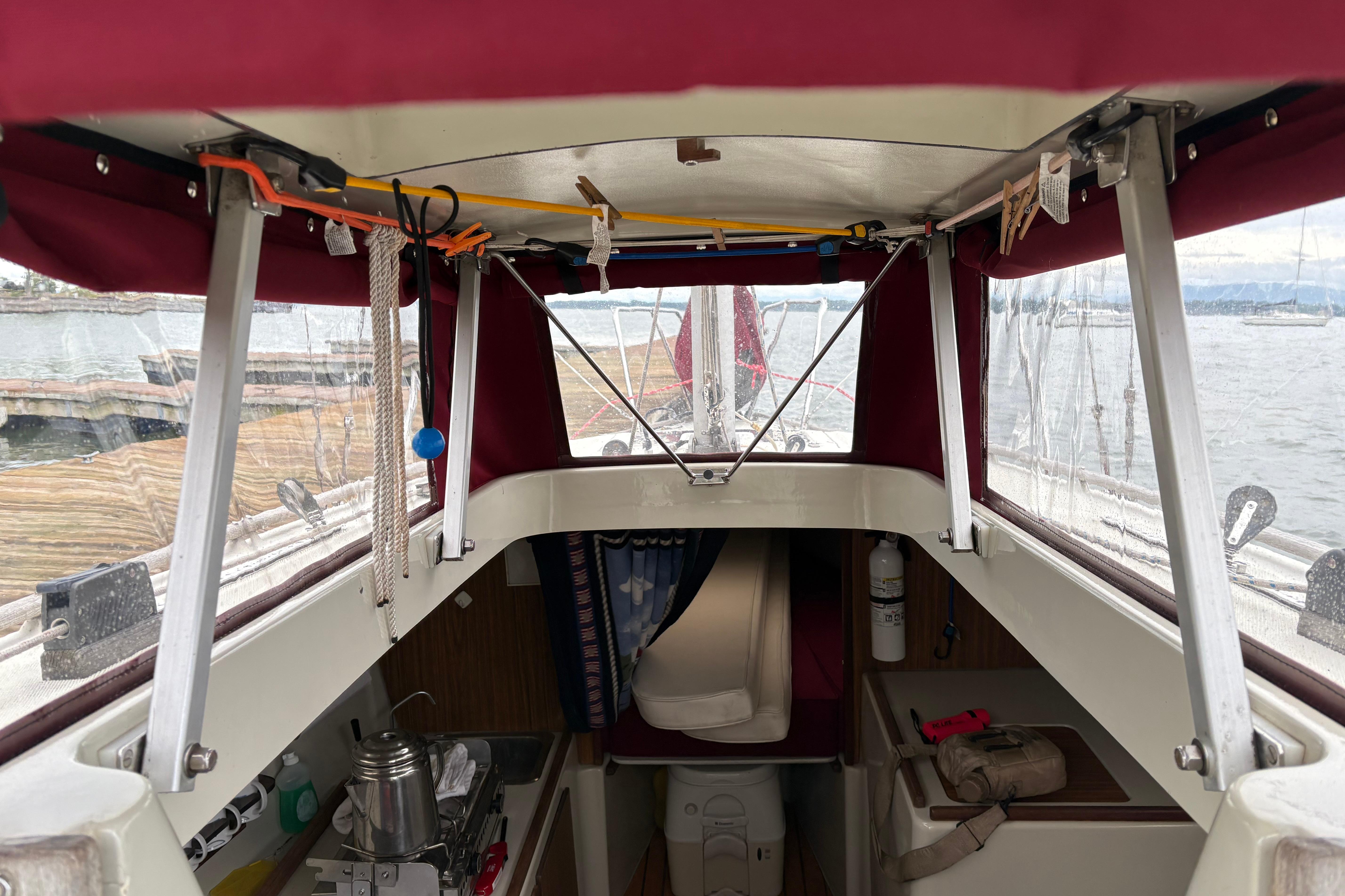 Slide: The Image of Interior view of a 1983 Sonic 23 sailboat with red canopy and dockside scenery. - 17