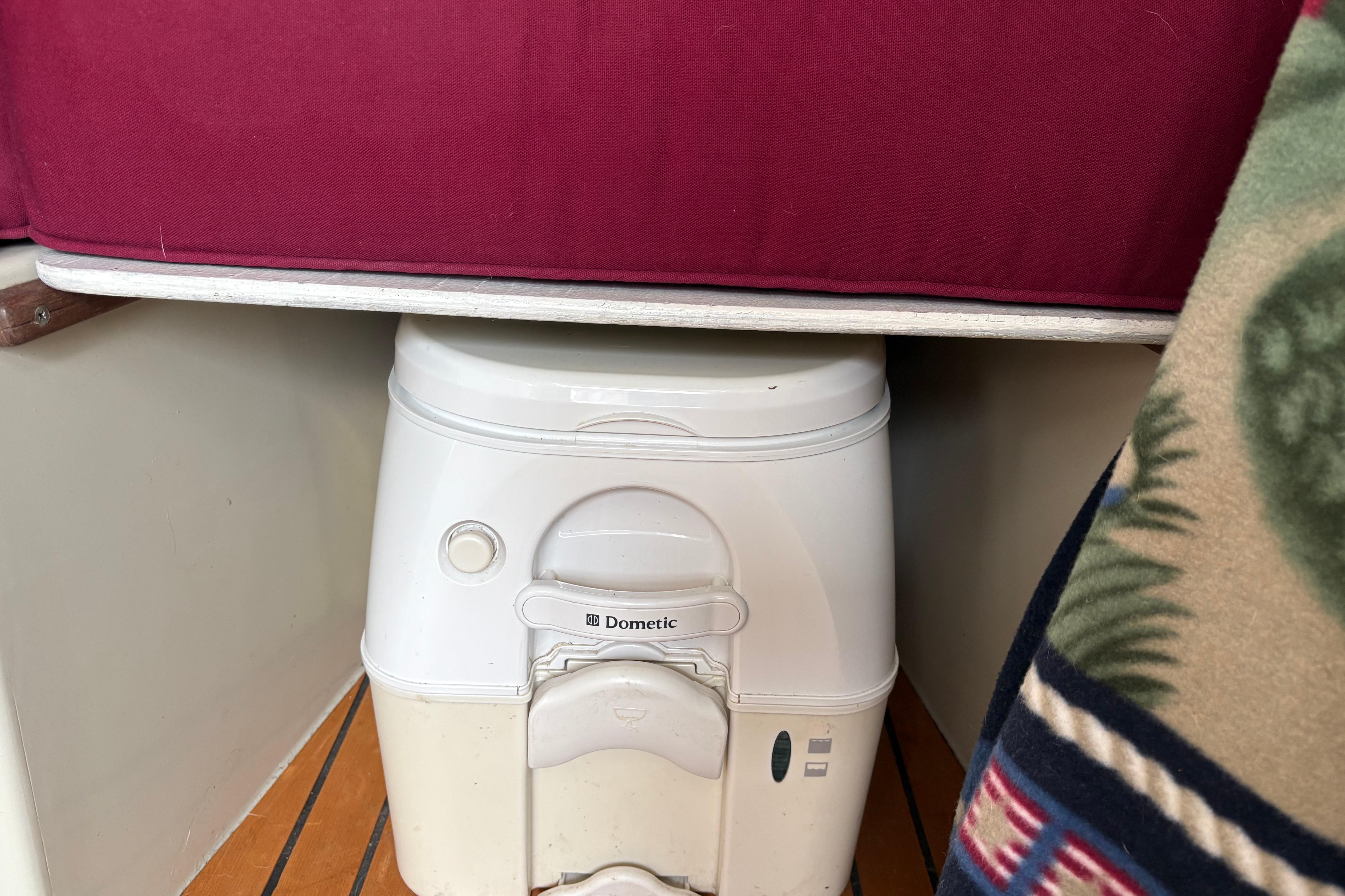 Slide: The Image of Portable Dometic toilet under red cushion in 1983 Sonic 23 boat interior. - 23