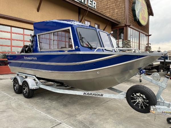 Slide: The Image of 2024 Spartan 200 Astoria boat on Karavan trailer, blue and silver, parked outside. - 1