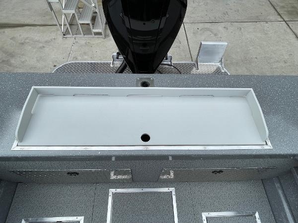 Slide: The Image of 2024 Spartan 200 Astoria boat deck with storage compartments and motor. - 17