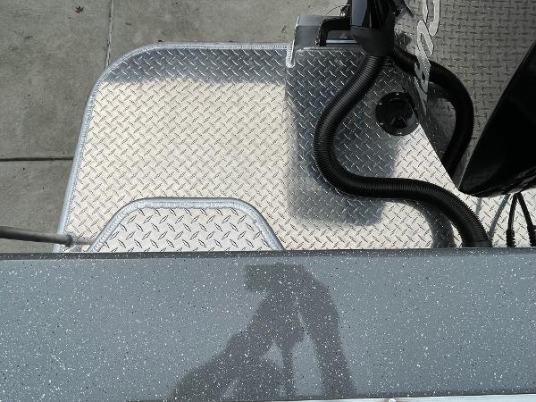 Slide: The Image of 2024 Spartan 200 Astoria boat deck with diamond plate flooring and engine components. - 19