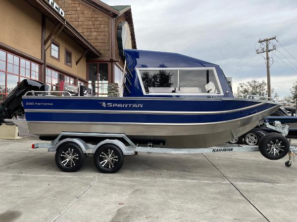 Slide: The Image of 2024 Spartan 200 Astoria boat on a Karavan trailer outside a building. - 2