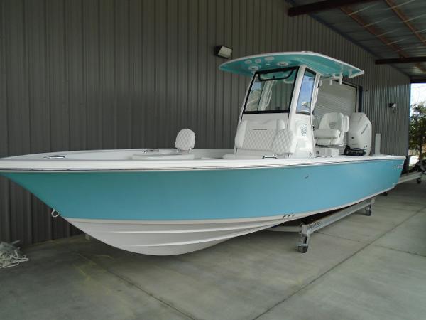 Slide: The Image of 2024 Sportsman 267 boat with blue hull and white interior, docked in a covered area. - 0