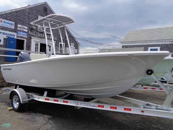 Slide: The Image of 2018 Sportsman Island Reef 19 Center Console boat on trailer, parked near a building. - 0