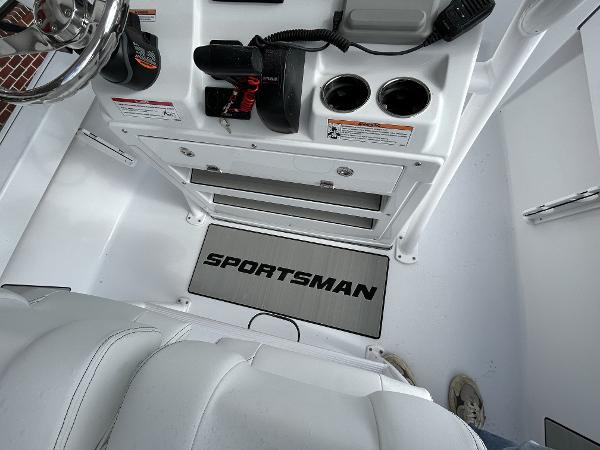 Slide: The Image of 2024 Sportsman Masters 227 Bay Boat interior console with steering wheel and storage compartments. - 16