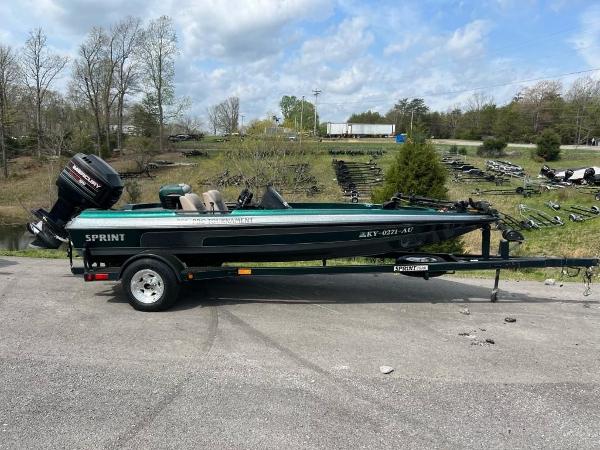 Slide: The Image of 1999 Sprint 286 Pro boat on trailer with outboard motor in a rural setting. - 0