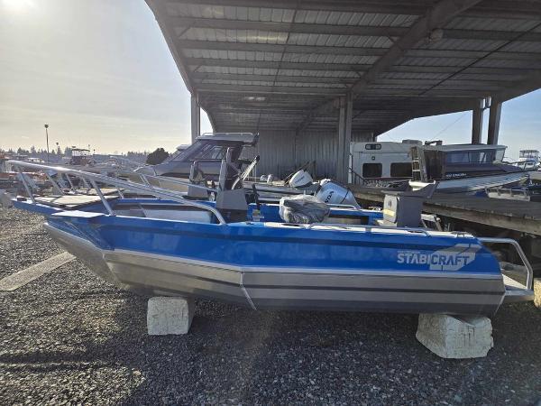 Slide: The Image of 2024 Stabicraft 1550 Frontier boat in blue, parked under a metal canopy. - 1