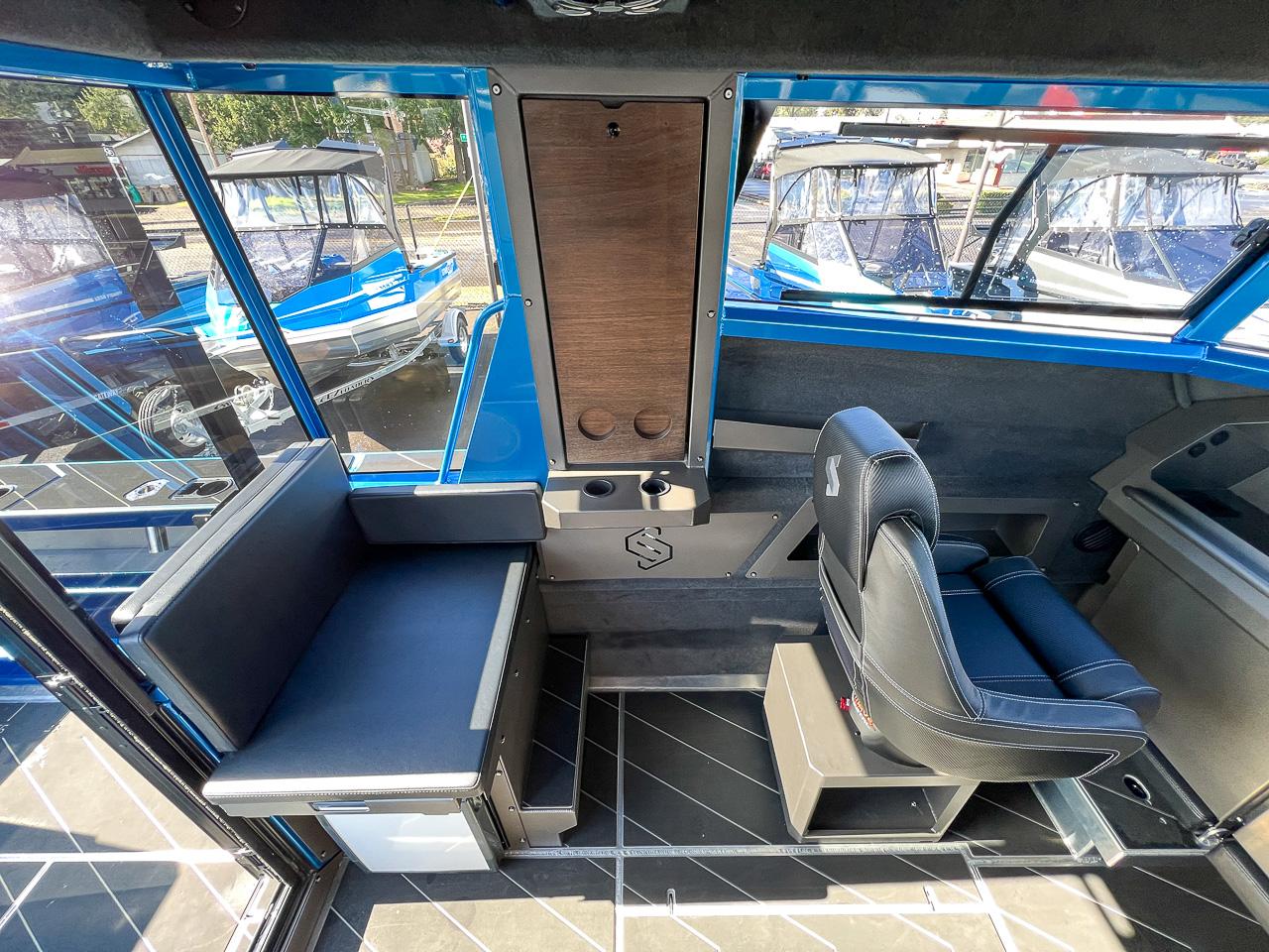 Slide: The Image of Interior of 2023 Stabicraft 2500 Ultracab XL, featuring seating and windows with docked boats outside. - 16