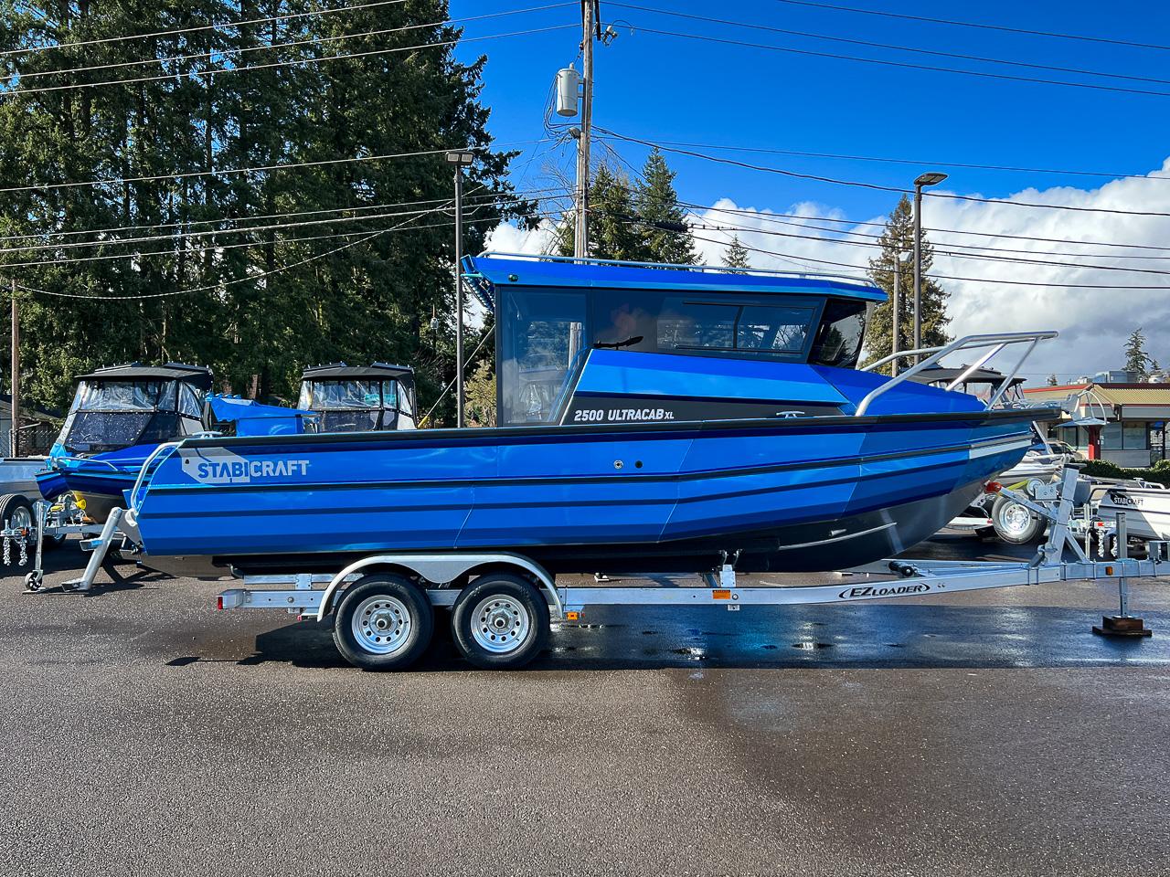 Slide: The Image of 2023 Stabicraft 2500 Ultracab XL boat on trailer, blue exterior, parked outdoors. - 2