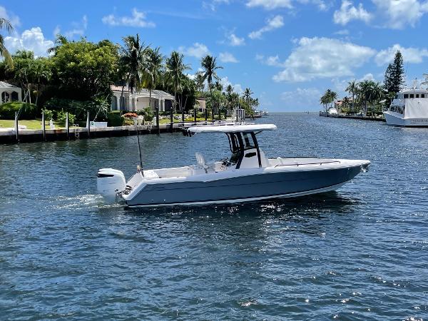 Slide: The Image of 2023 Stamas 31T Aventura boat cruising on a sunny, palm-lined waterway. - 1
