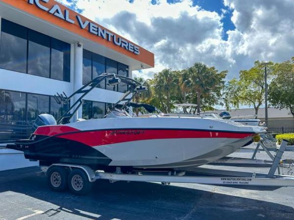 Slide: The Image of 2024 Starcraft SVX 231 OB DH boat on trailer outside a dealership under a cloudy sky. - 0
