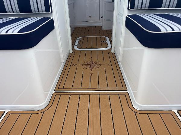 Slide: The Image of 2025 Steiger Craft 255 Annapolis boat interior with striped seating and compass design flooring. - 25