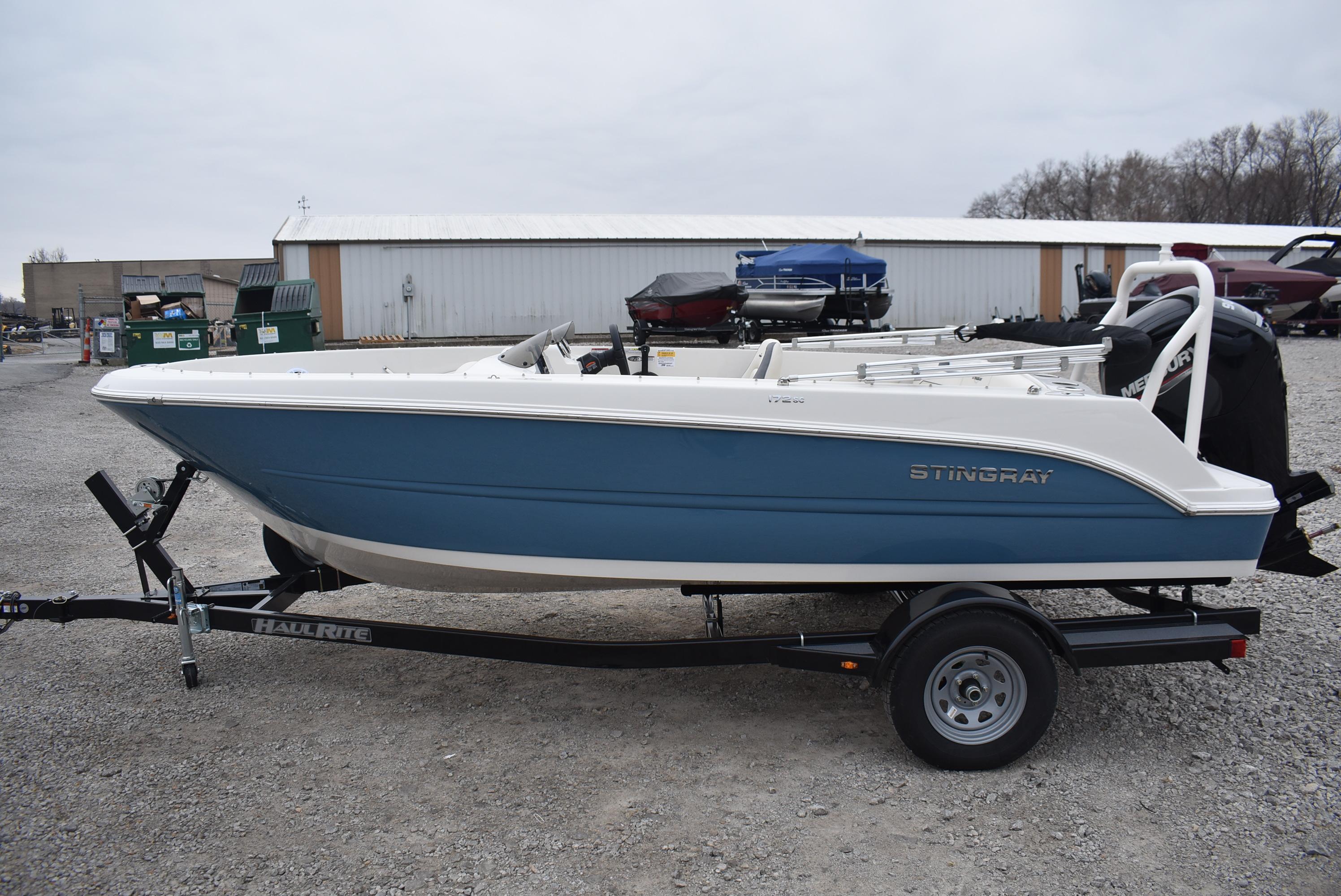 Slide: The Image of 2023 Stingray 172SC boat on trailer, blue and white design, outdoor setting. - 2
