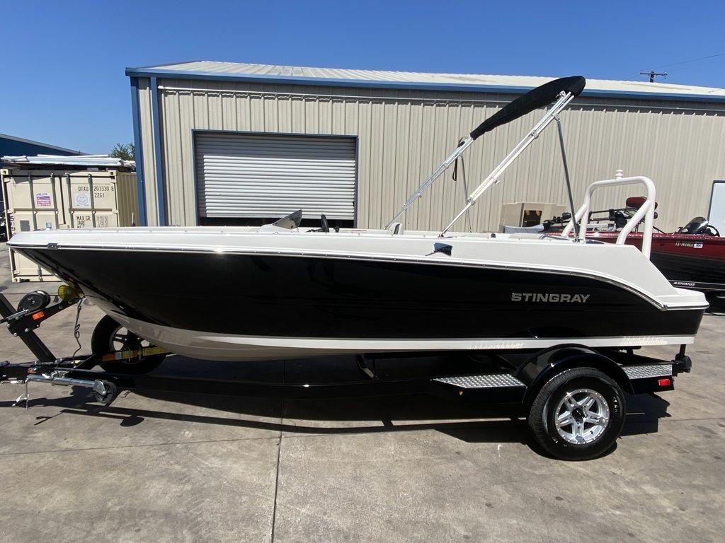 Slide: The Image of 2024 Stingray 172SC boat on trailer, black and white hull, parked outside. - 0
