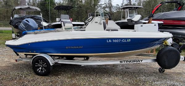 Slide: The Image of 2019 Stingray 186 CC boat on trailer, blue and white design, parked outdoors. - 0