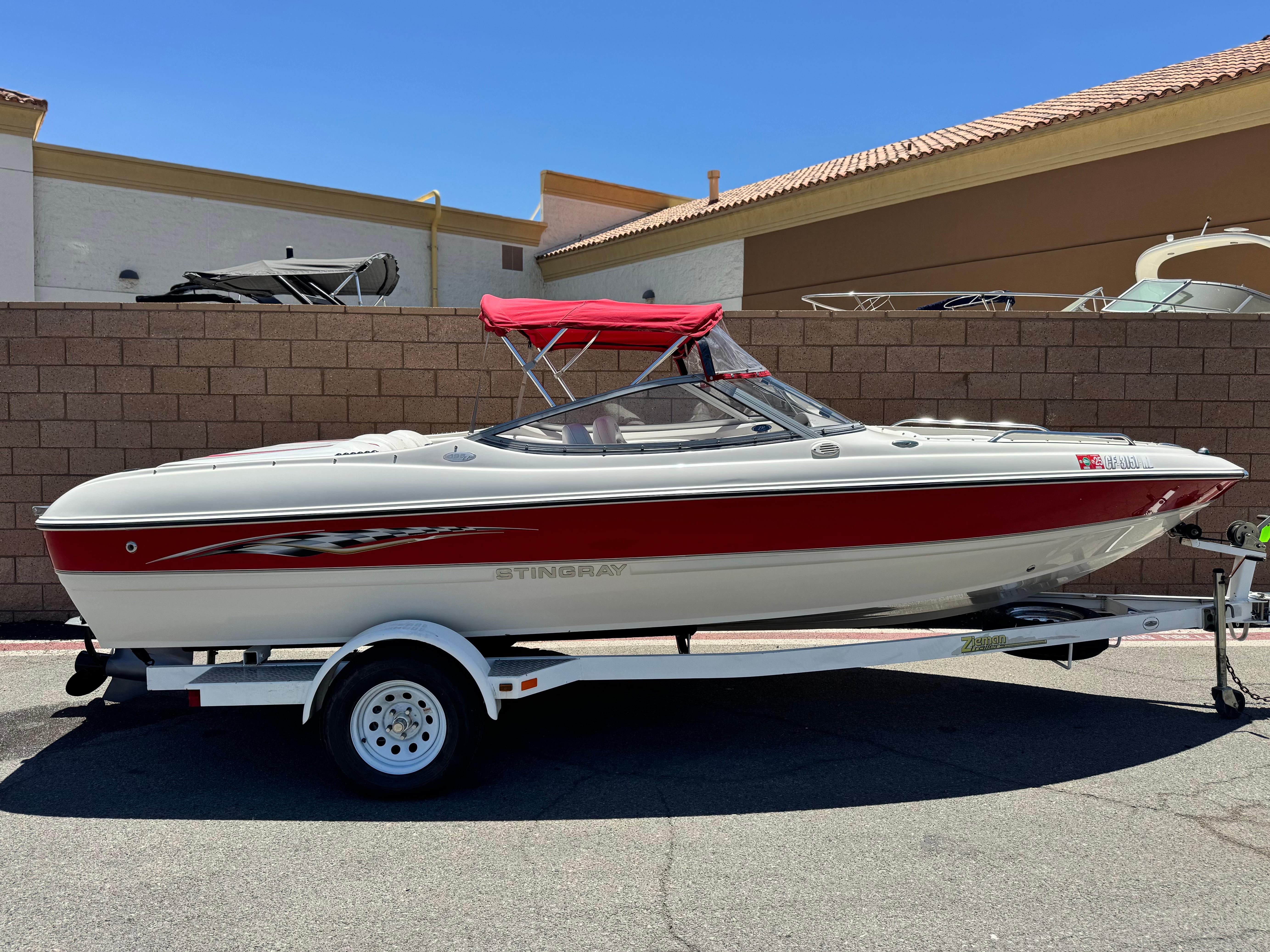 Slide: The Image of 2006 Stingray 195 LR boat with red accents and canopy on a trailer. - 0