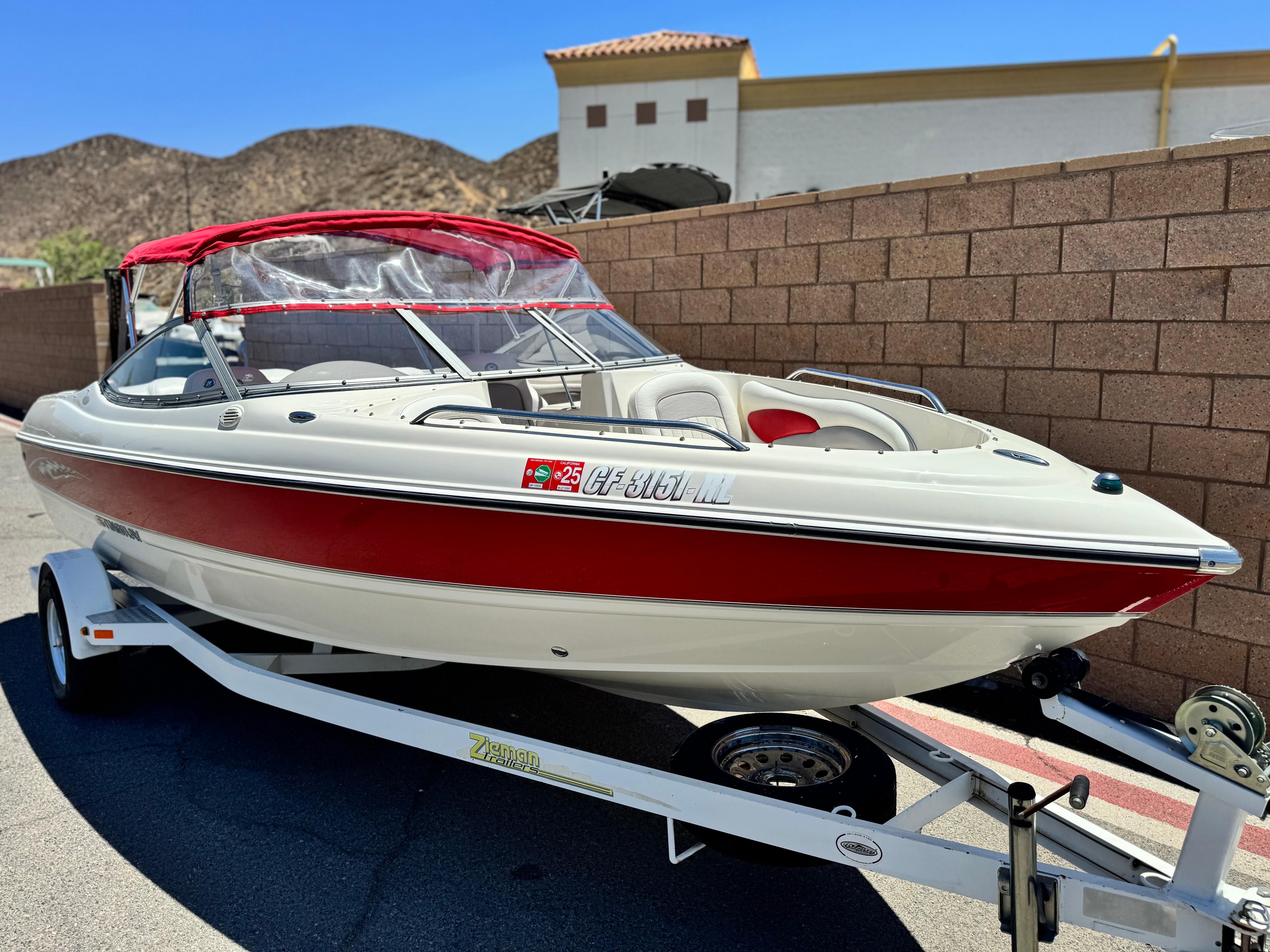 Slide: The Image of 2006 Stingray 195 LR boat with red accents on a trailer, parked by a brick wall. - 1