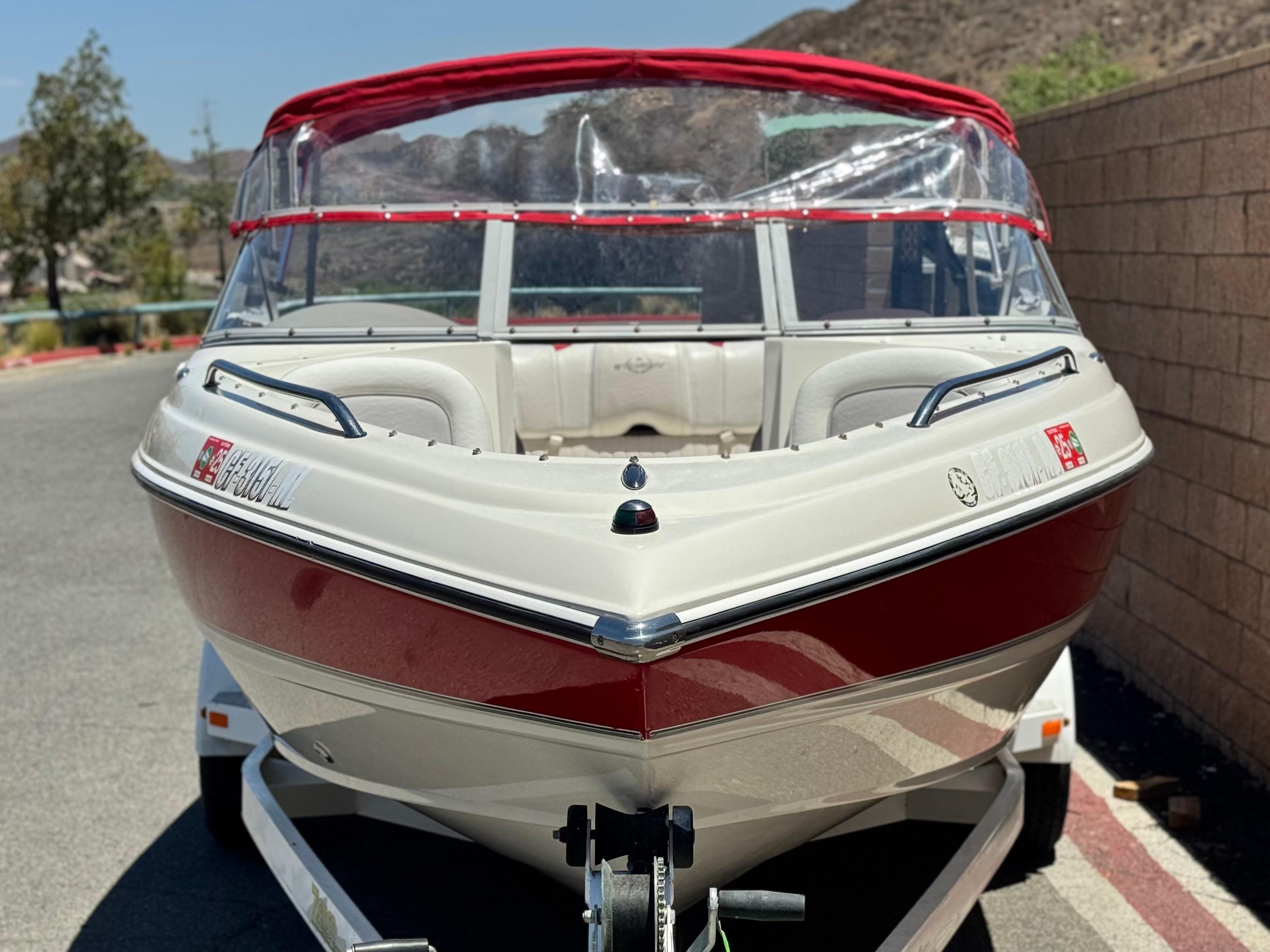 Slide: The Image of 2006 Stingray 195 LR boat with red canopy, parked on a trailer. - 2