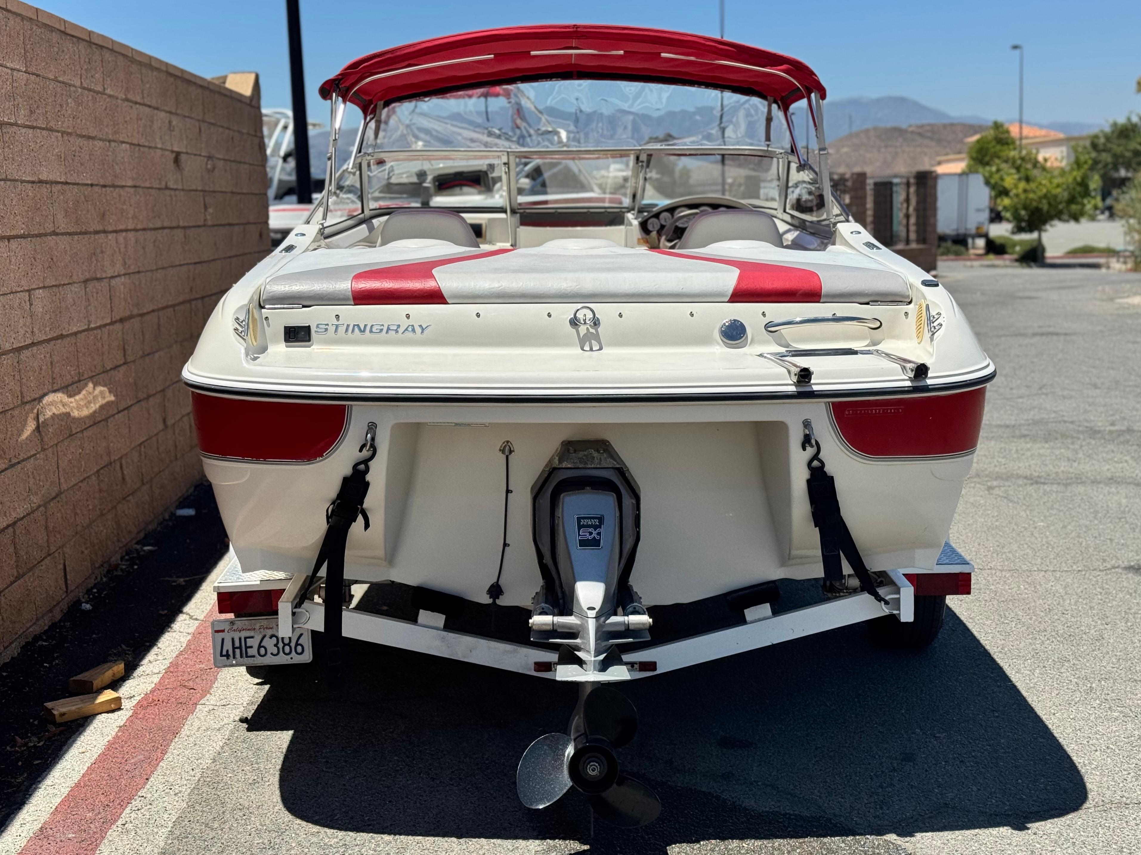 Slide: The Image of 2006 Stingray 195 LR boat with red accents, parked on a trailer in a sunny area. - 4