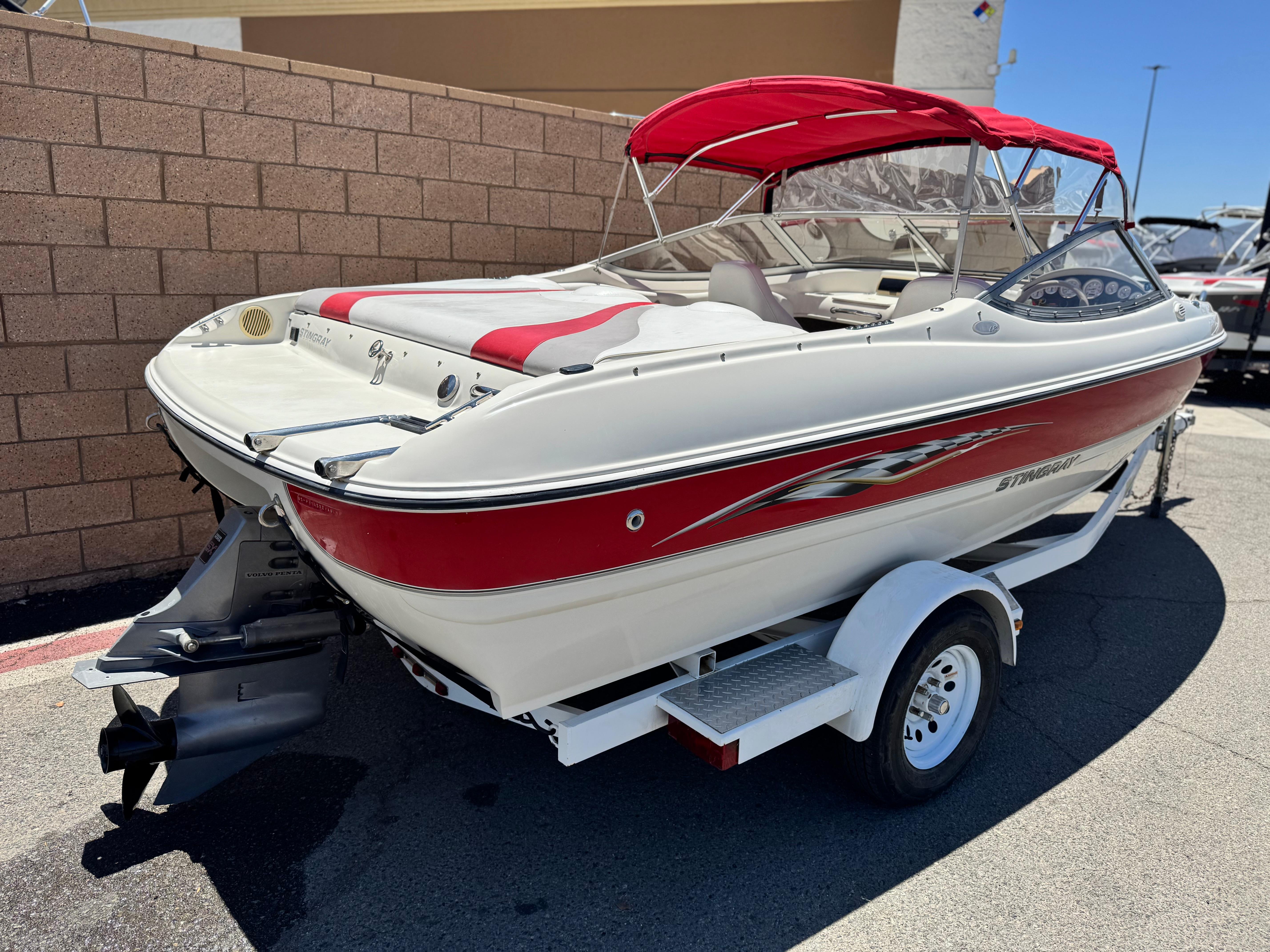Slide: The Image of 2006 Stingray 195 LR boat with red accents on a trailer, parked outdoors. - 5