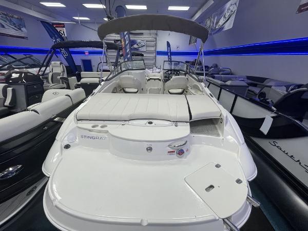 Slide: The Image of 2022 Stingray 215LR boat in showroom, rear view with seating and canopy. - 2