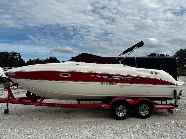 Slide: The Image of 2011 Stingray 250 LR boat on a red trailer under a cloudy sky. - 0