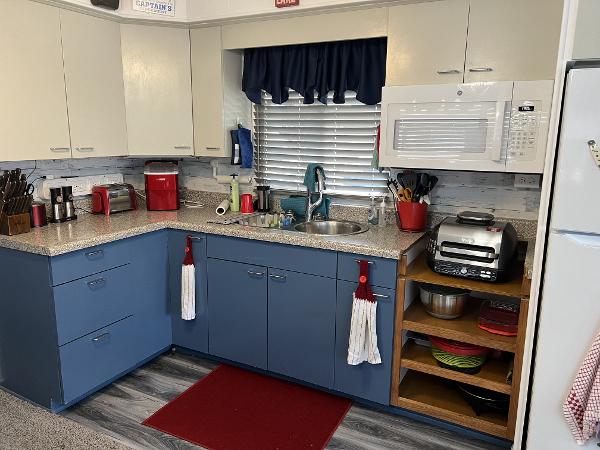 Slide: The Image of 1987 Sumerset Houseboat kitchen with blue and white cabinets, modern appliances, and red accents. - 5