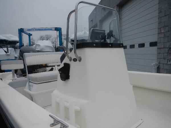 Slide: The Image of 2016 Sundance 17 Center Console boat with windshield and seating, docked near a marine facility. - 17