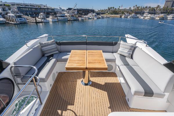 Slide: The Image of Sunseeker Manhattan 55 2022 yacht with spacious deck seating and wooden table in marina. - 12
